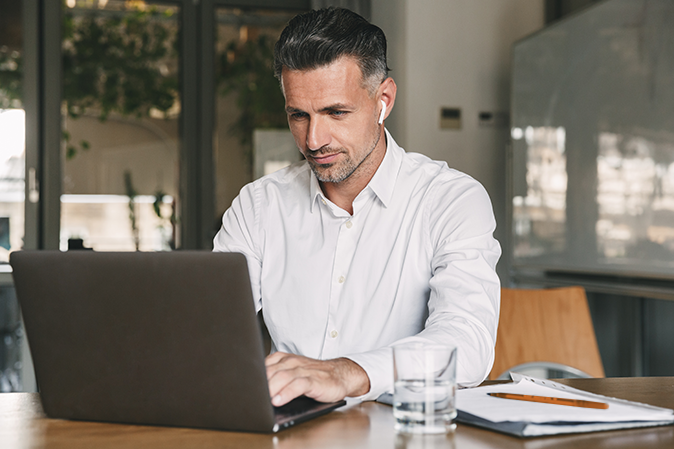 Middle-aged man in an office typing on a laptop