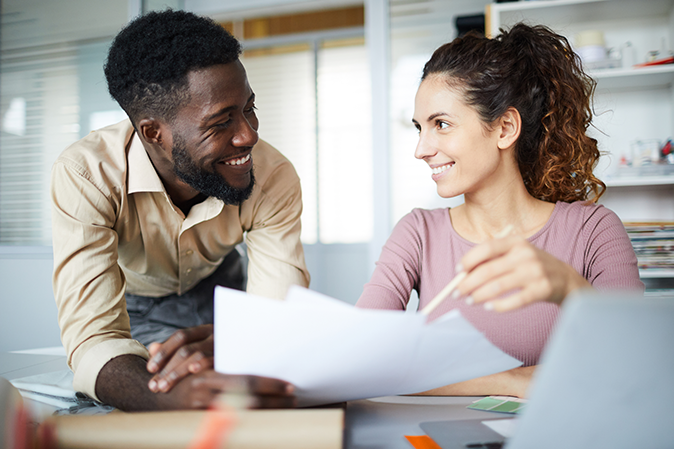 Successful designers discussing data in documents and their new ideas at working meeting